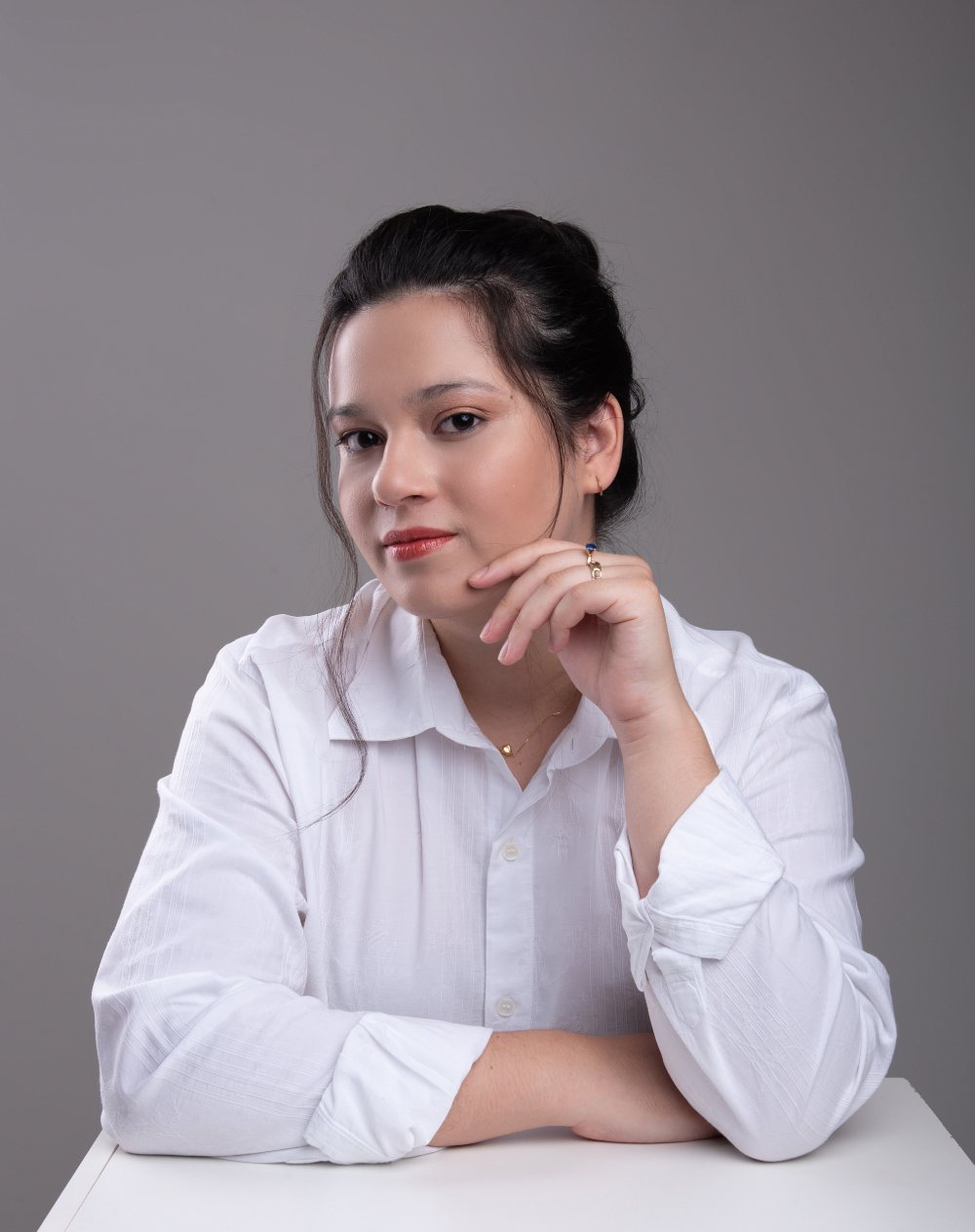 Retrato de Karine Lima, psicóloga, com expressão serena e camisa branca